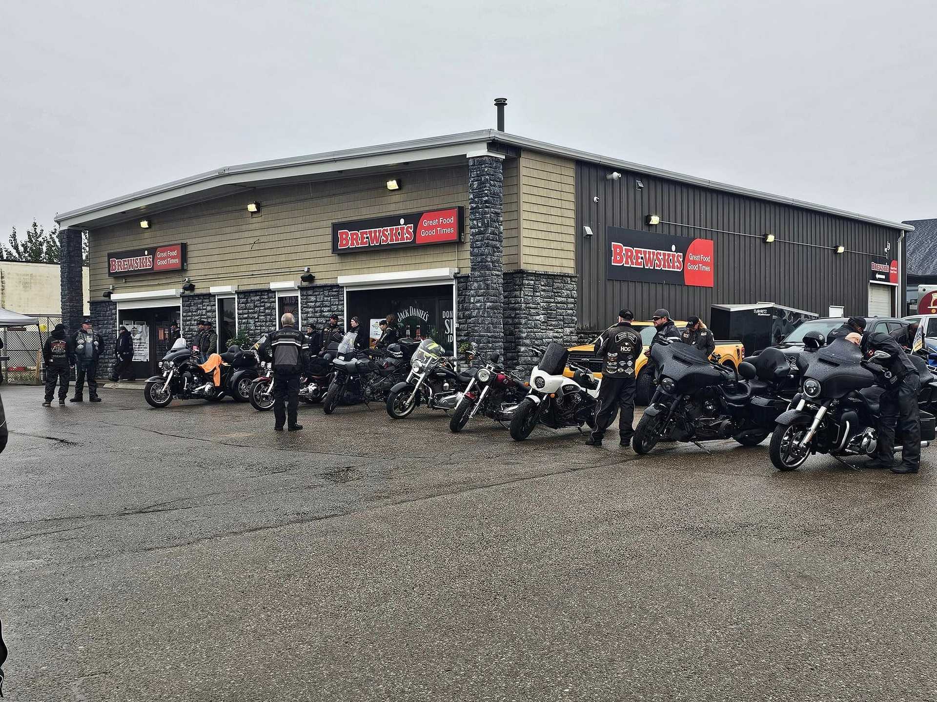 A group of motorcyclists gathered outside Brewsha's coffee shop on a cloudy day.